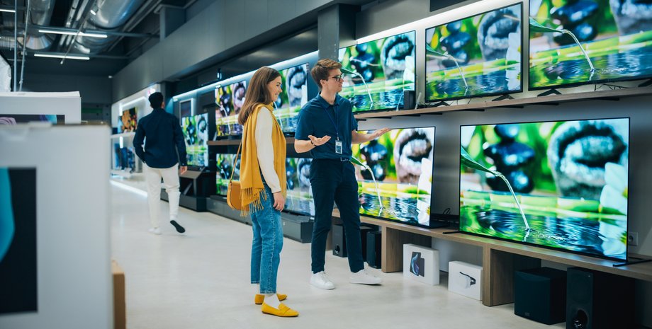 Девушка с консультатном выбирают телевизор в магазине